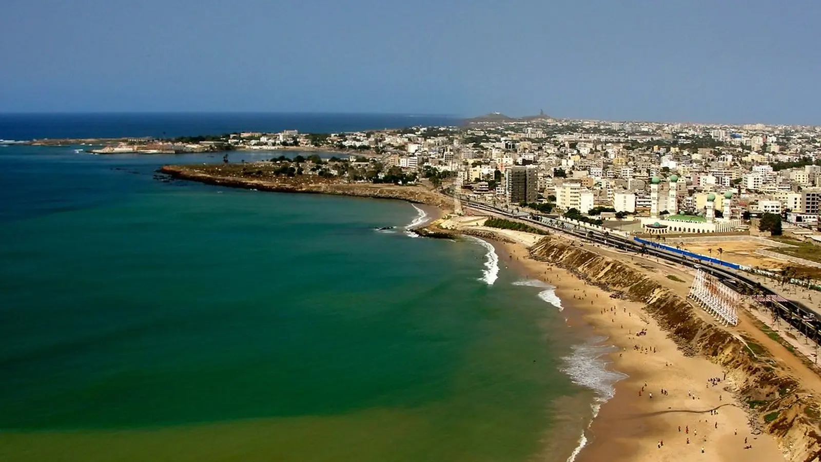 vue aérienne d'une plage animée longeant une ville côtière avec immeubles et voies ferrées
