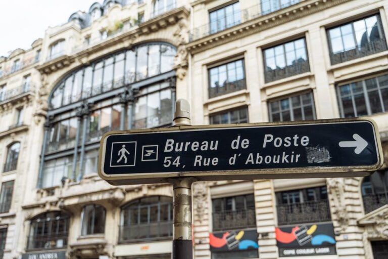 Paris street sign directing to the Bureau de Poste on Rue d'Aboukir, captured with classic Parisian architecture in the background.