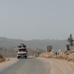 Truck driving on a dusty desert road with mountains