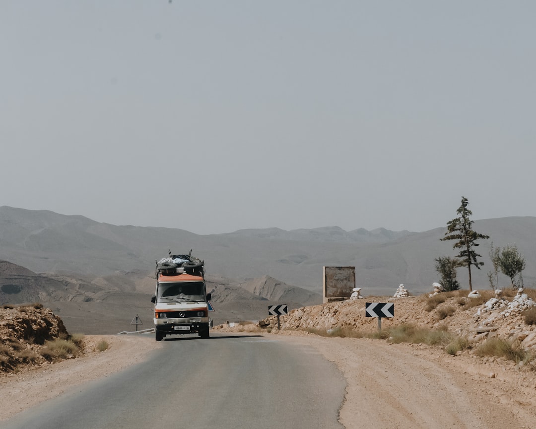 Truck driving on a dusty desert road with mountains